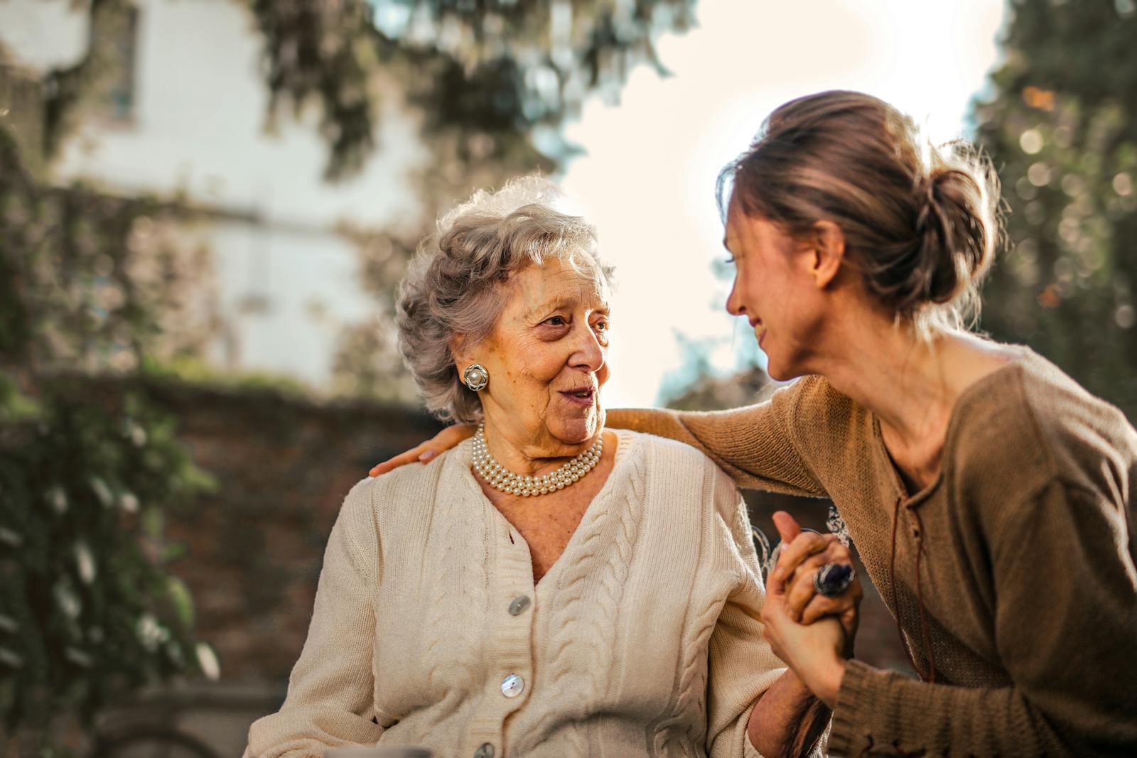 A caregiver sharing a warm, unguarded moment with an older adult in golden afternoon light